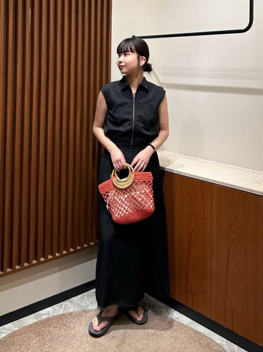 ブラック系のワンピース、オレンジ系のかごバッグを着用したレディースの夏コーディネートの1枚目の写真