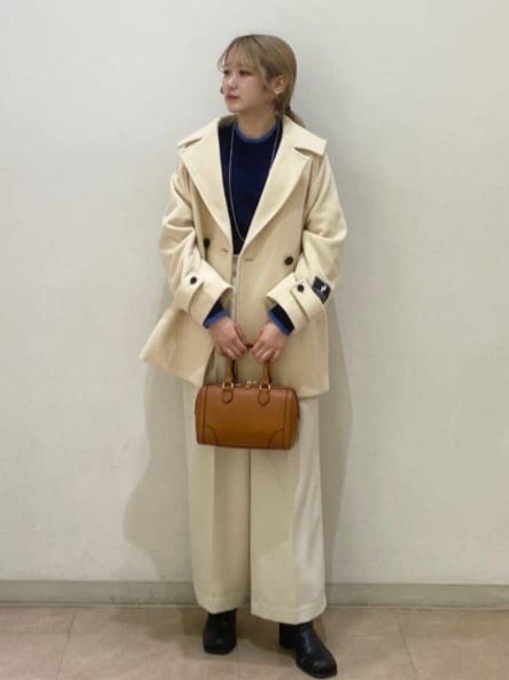 ブラウン系のトートバッグ、イエロー系のその他アウター、ブルー系のニット/セーターを着用したレディースの冬コーディネートの1枚目の写真