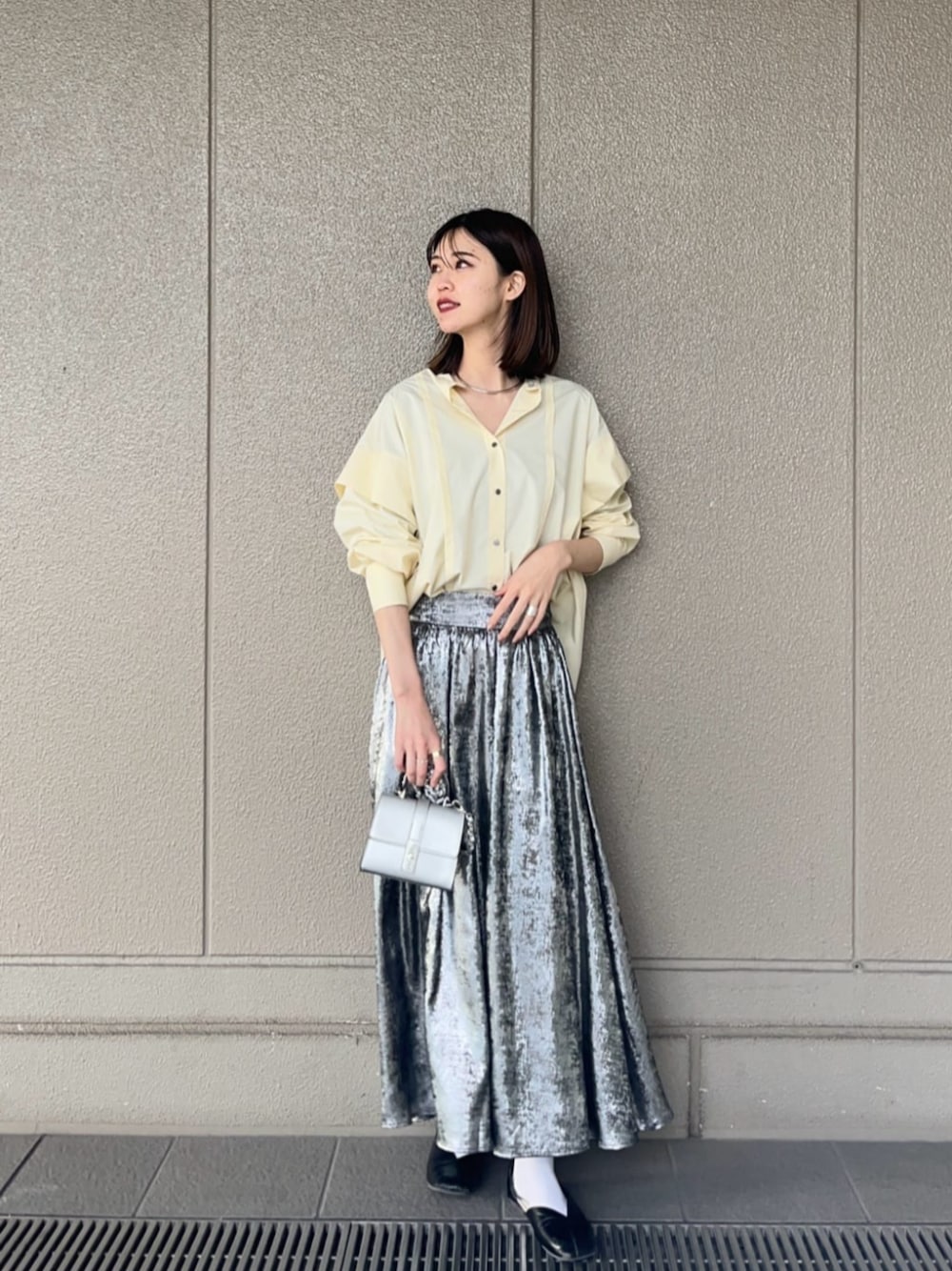 シルバー系のスカート、シルバー系のショルダーバッグ、イエロー系のシャツ/ブラウスを着用したレディースの春コーディネートの1枚目の写真