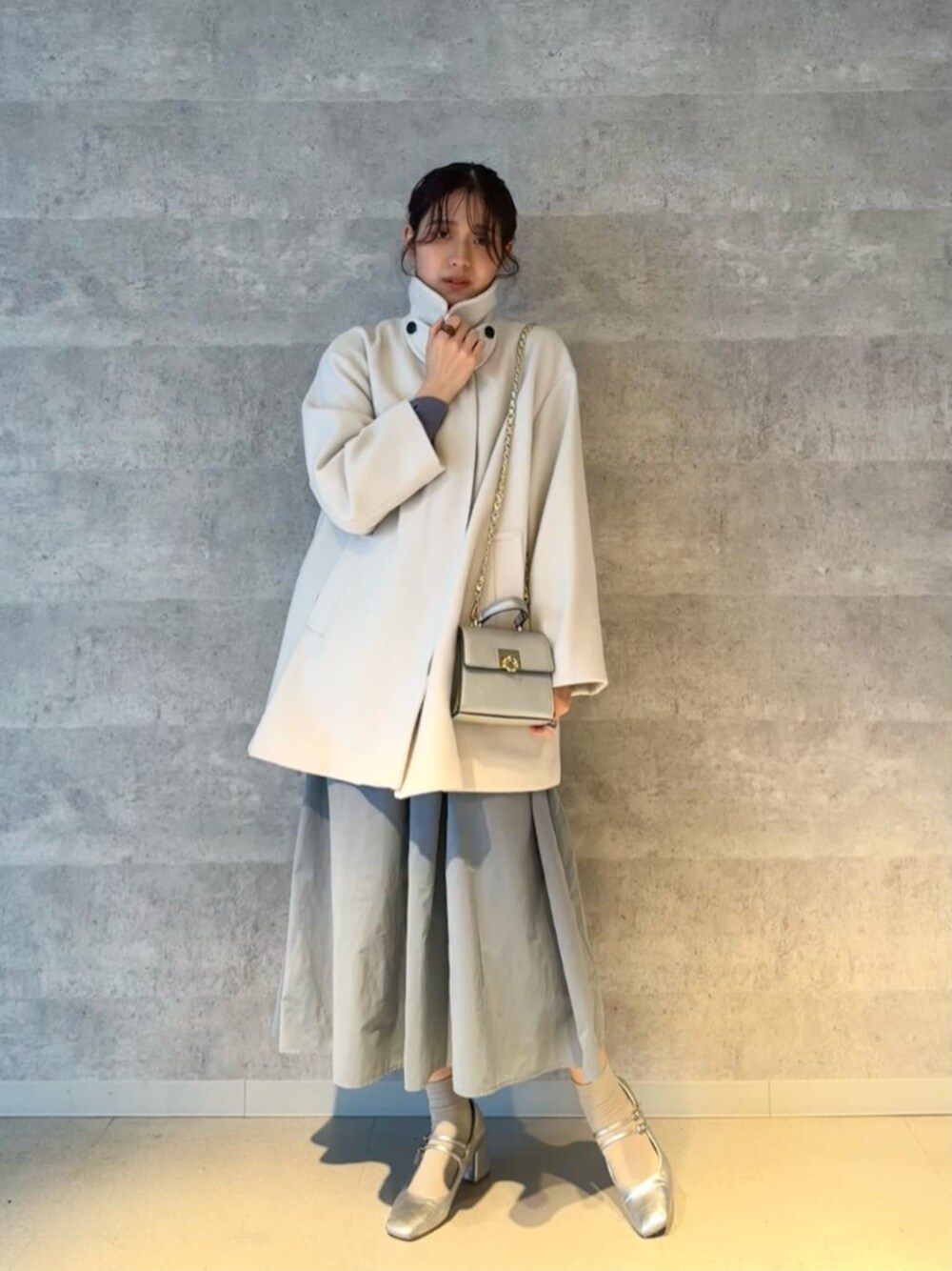 シルバー系のビジネスバッグ、シルバー系のパンプス、ブルー系のワンピースを着用したレディースの冬コーディネートの1枚目の写真