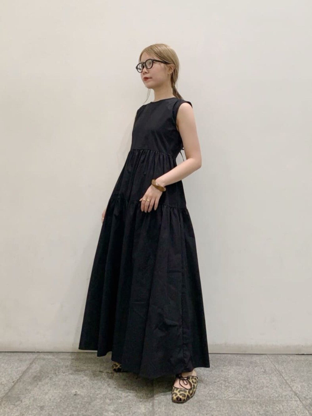 ブラック系のワンピース、ブラック系のサングラス、ブラウン系のバングル/リストバンドを着用したレディースの春コーディネートの1枚目の写真