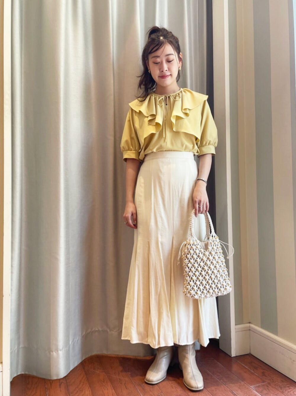 ホワイト系のショルダーバッグ、イエロー系のシャツ/ブラウス、ホワイト系のスカートを着用したレディースの春コーディネートの1枚目の写真