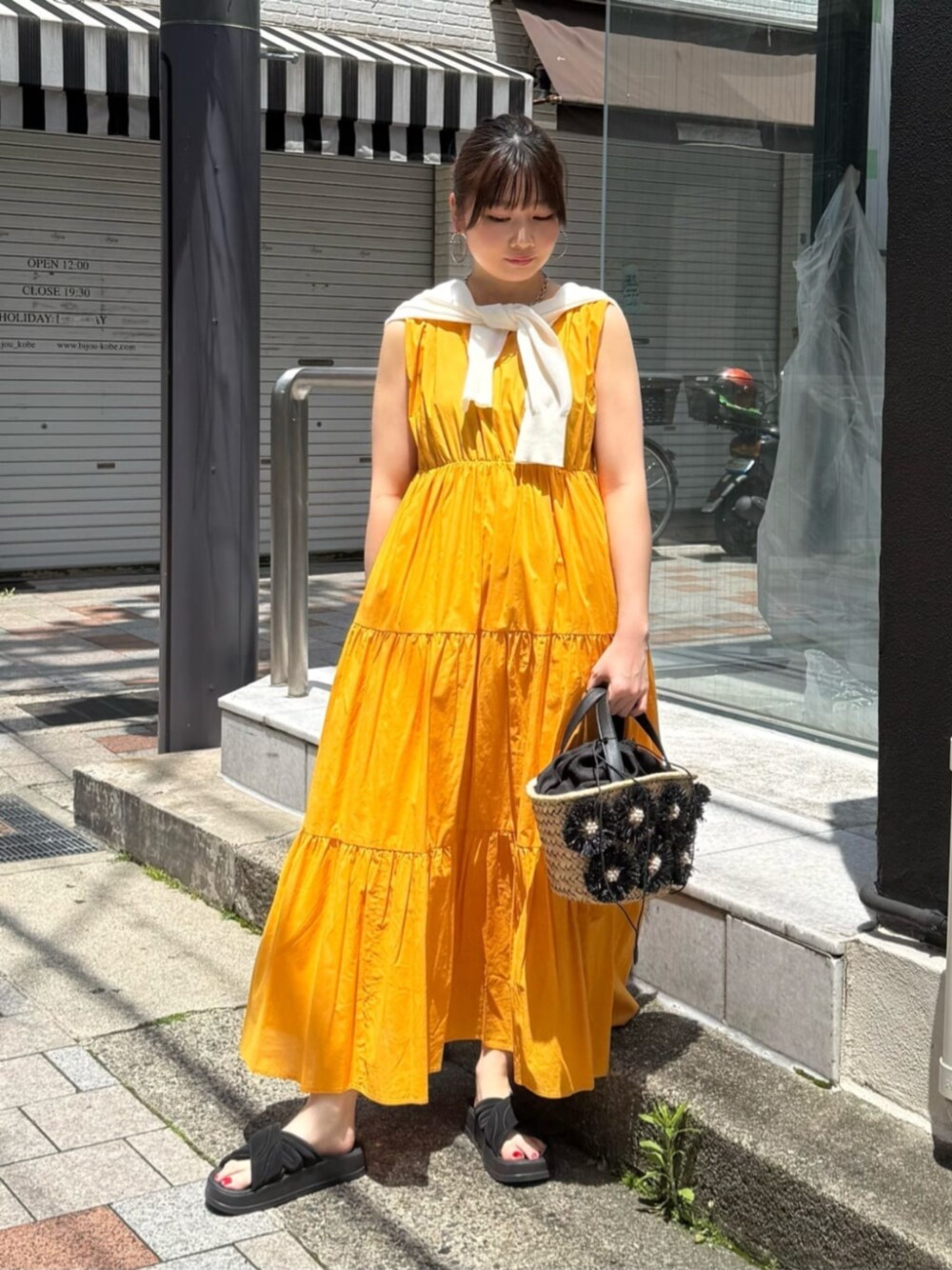 オレンジ系のワンピース、ホワイト系のカーディガン/ボレロを着用したレディースの夏コーディネートの1枚目の写真