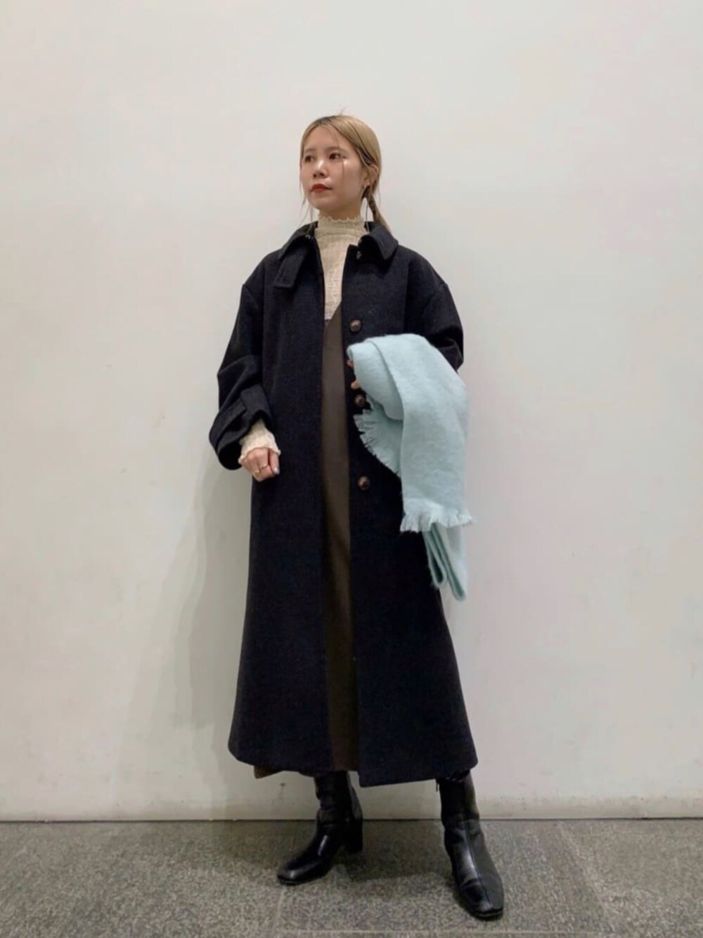 ブラック系のブーツ、ホワイト系のTシャツ/カットソー、ブラック系のステンカラーコートを着用したレディースの冬コーディネートの1枚目の写真