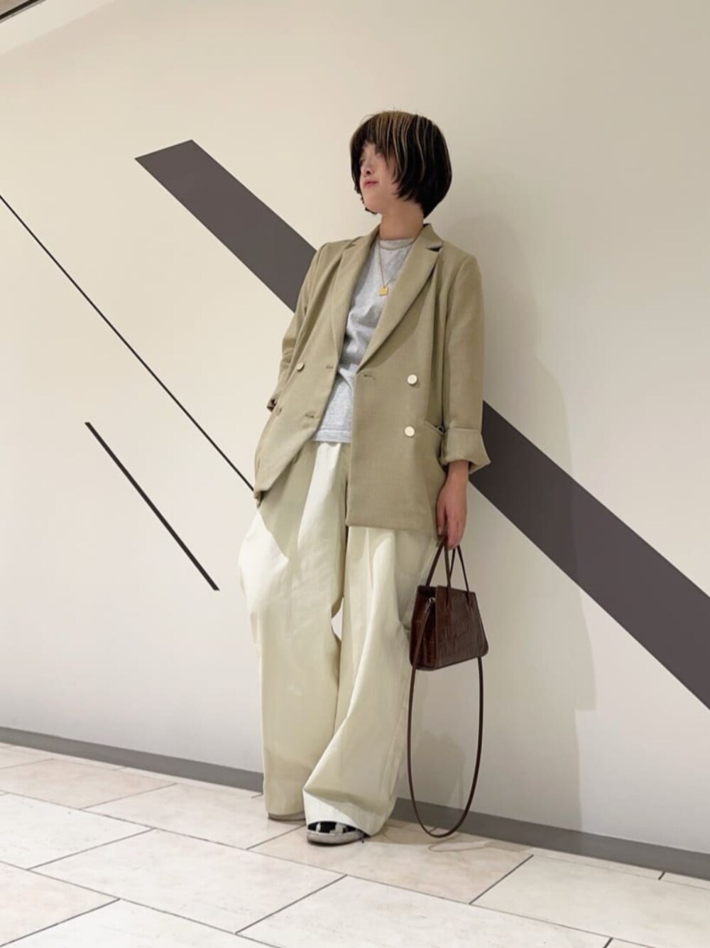 ベージュ系のテーラードジャケット、ベージュ系のスラックスを着用したレディースの春コーディネートの1枚目の写真