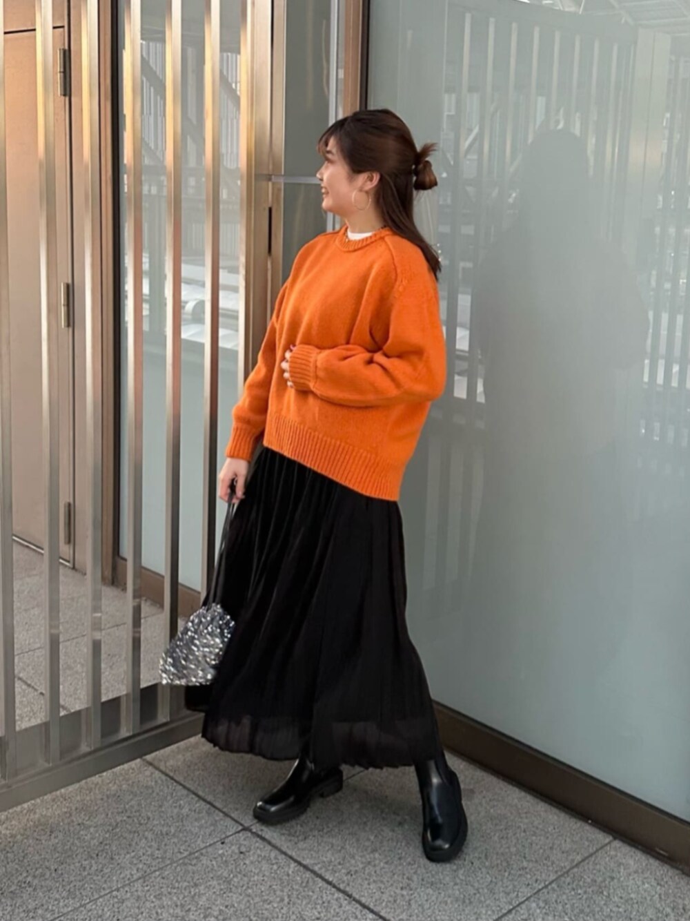 グレー系のビジネスバッグ、ブラック系のブーツ、ホワイト系のTシャツ/カットソーを着用したレディースの秋コーディネートの1枚目の写真