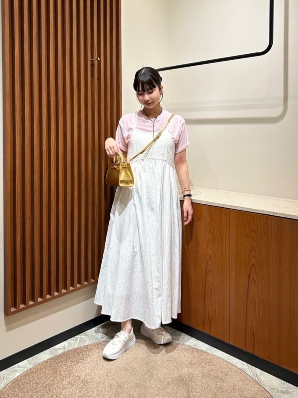 ホワイト系のスニーカー、ホワイト系のワンピース、ピンク系のTシャツ/カットソーを着用したレディースの春コーディネートの1枚目の写真