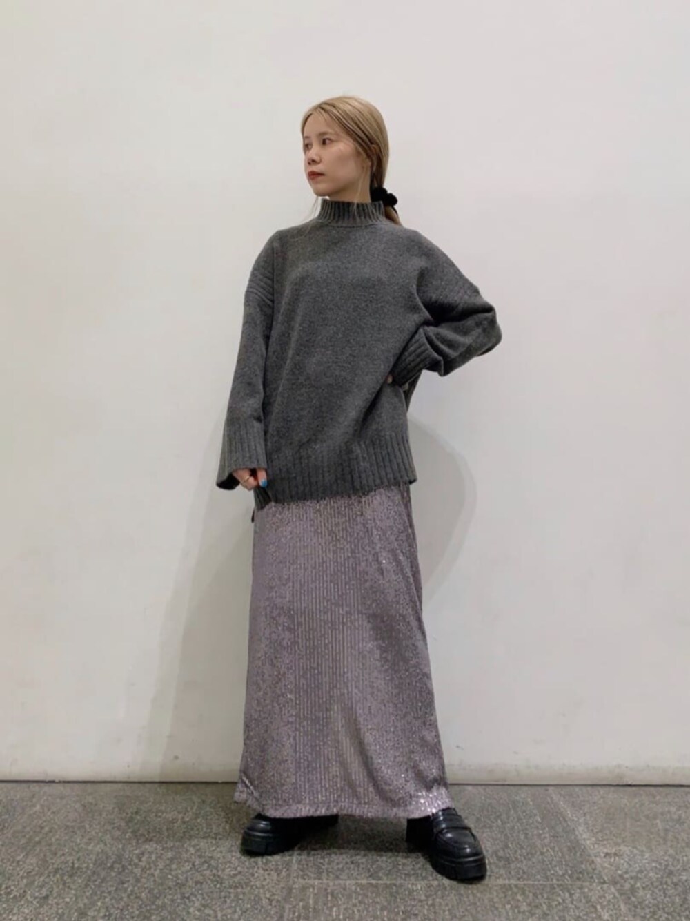 グレー系のスカート、グレー系のニット/セーターを着用したレディースの冬コーディネートの1枚目の写真