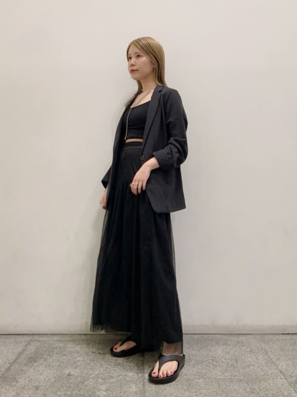 ブラック系のテーラードジャケット、ブラック系のキャミソール、ブラック系のスカートを着用したレディースの春コーディネートの1枚目の写真