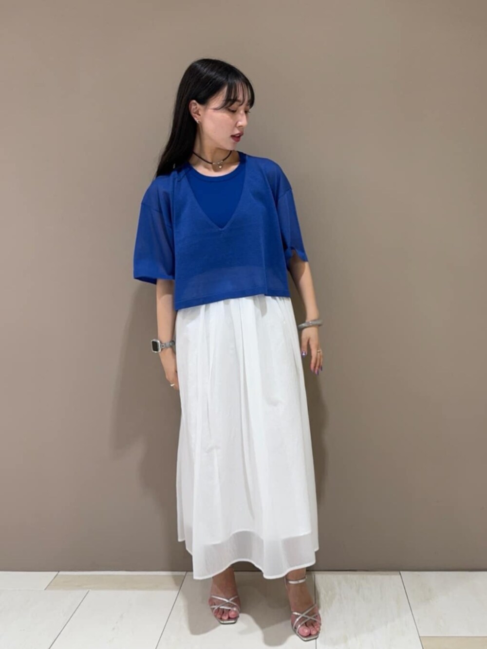 シルバー系のサンダル、ホワイト系のスカート、ブルー系のニット/セーターを着用したレディースの春コーディネートの1枚目の写真