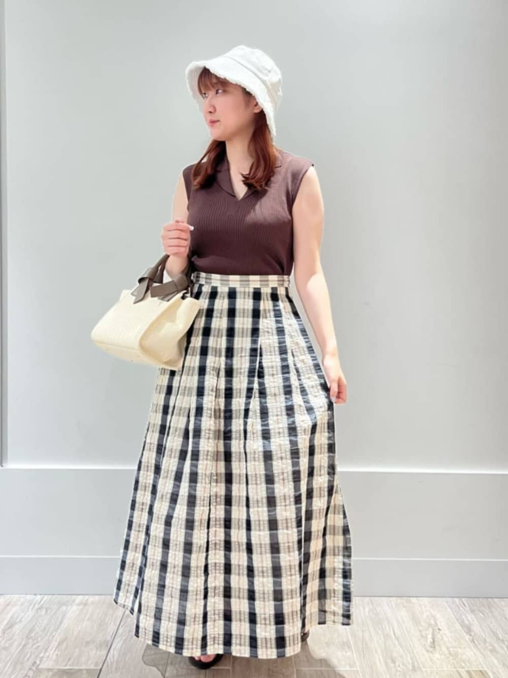 ベージュ系のスカート、ブラウン系のポロシャツを着用したレディースの夏コーディネートの1枚目の写真