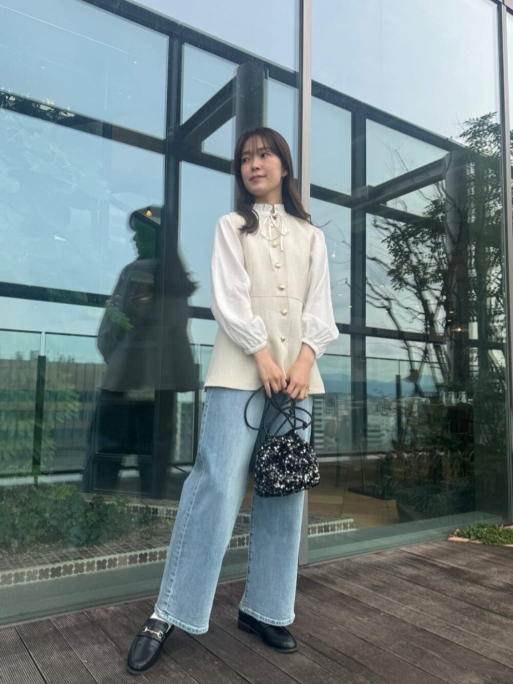 ブルー系のデニムパンツ、ブラック系のショルダーバッグ、ホワイト系のベストを着用したレディースの冬コーディネートの1枚目の写真