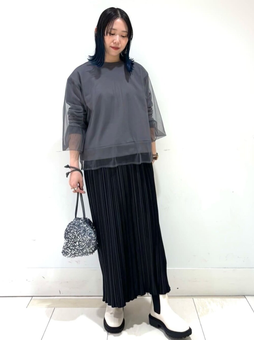 グレー系のビジネスバッグ、ホワイト系のブーツ、グレー系のスウェットを着用したレディースの冬コーディネートの1枚目の写真