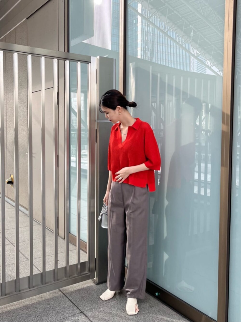 シルバー系のショルダーバッグ、レッド系のニット/セーター、グレー系のその他パンツを着用したレディースの春コーディネートの1枚目の写真