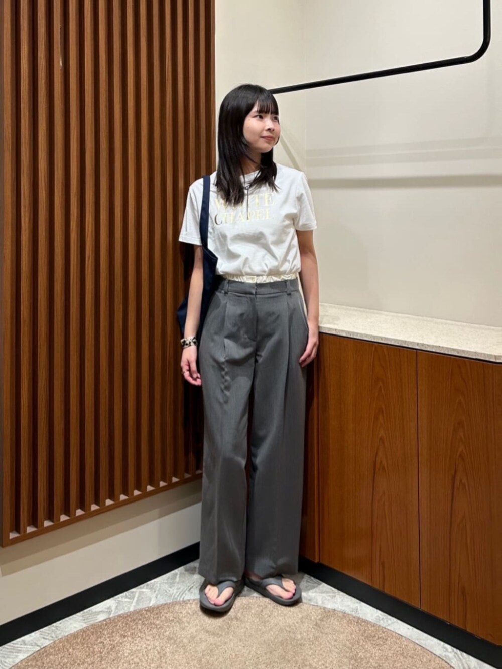 グレー系のスラックス、ホワイト系のTシャツ/カットソー、ベージュ系のバングル/リストバンドを着用したレディースの夏コーディネートの1枚目の写真