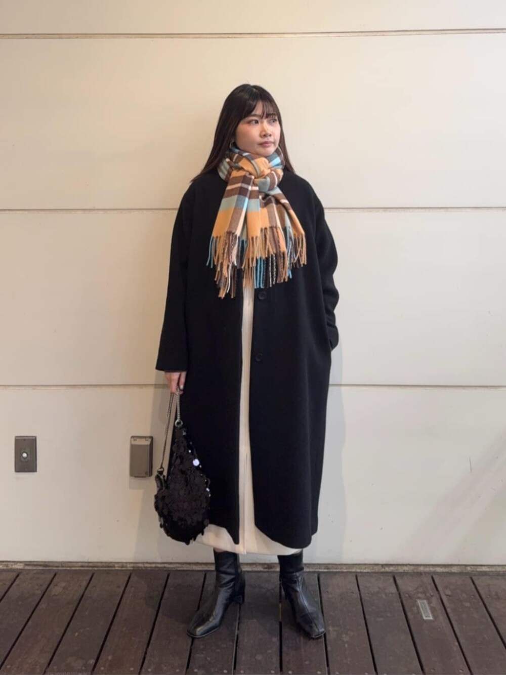 ブラック系のショルダーバッグ、ブラック系のノーカラーコート、グレー系のニット/セーターを着用したレディースの冬コーディネートの1枚目の写真