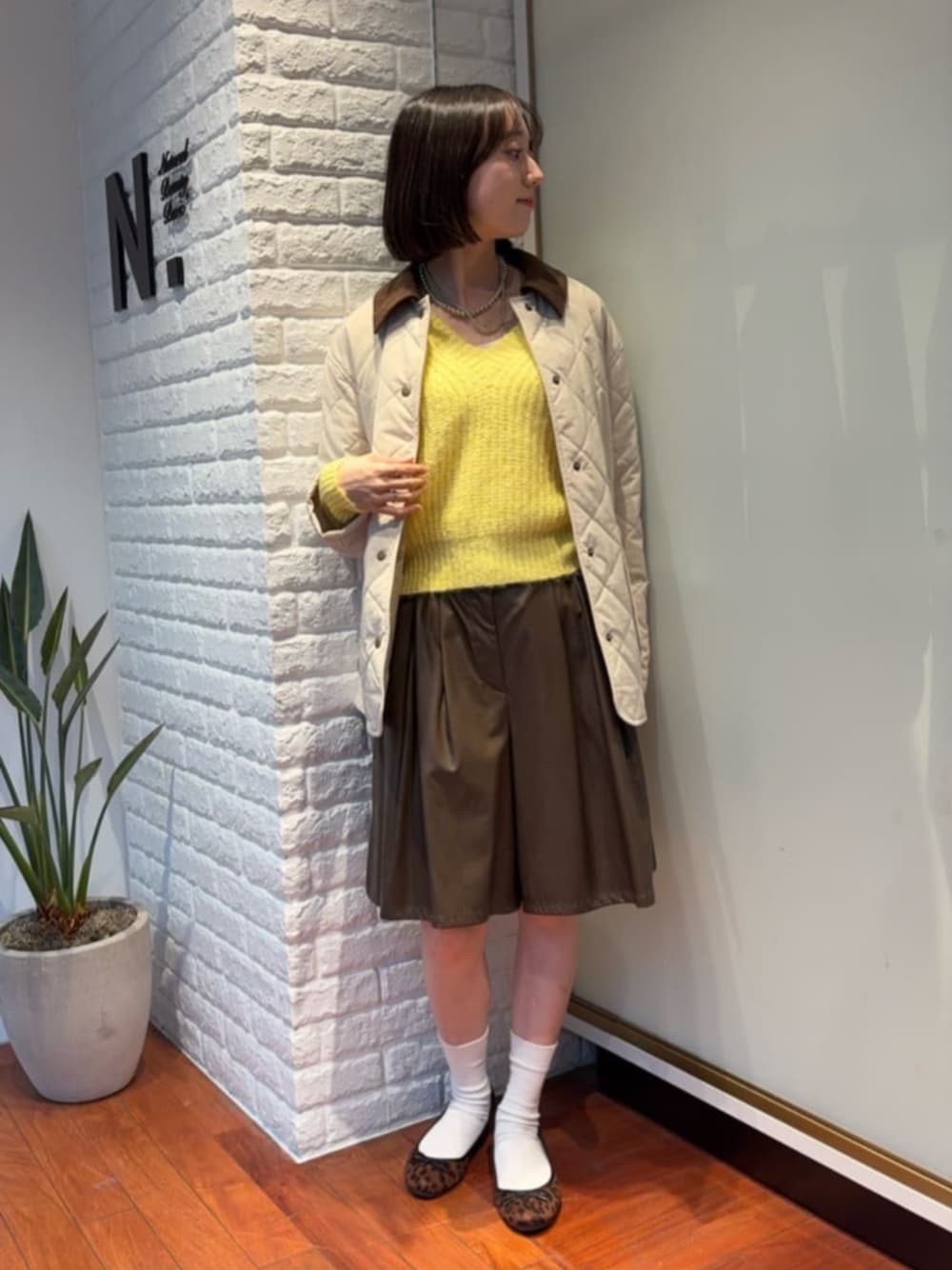 イエロー系のニット/セーター、ブラウン系のその他パンツ、ホワイト系のブルゾンを着用したレディースの秋コーディネートの1枚目の写真