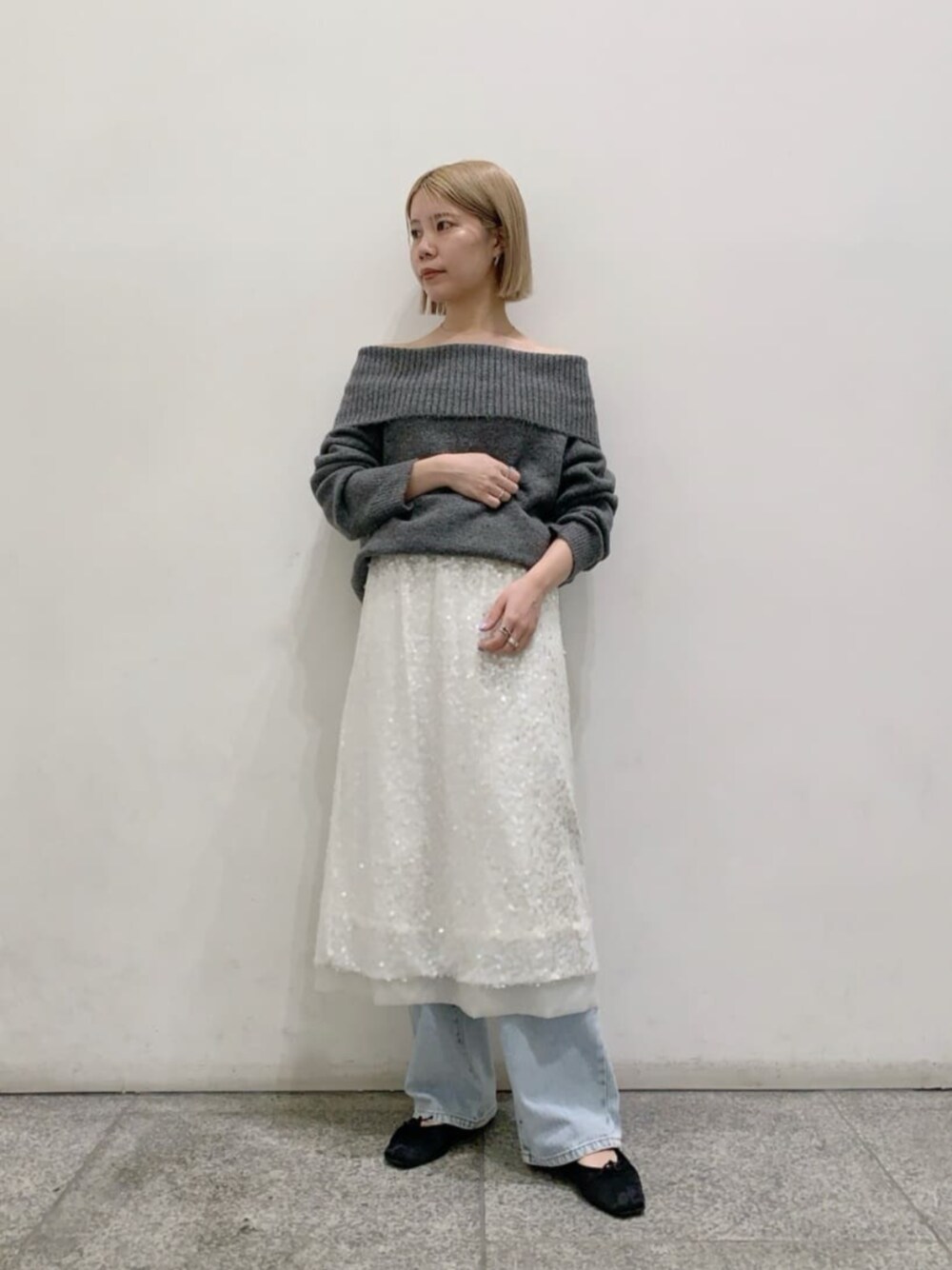 ブルー系のデニムパンツ、グレー系のニット/セーター、ホワイト系のスカートを着用したレディースの秋コーディネートの1枚目の写真