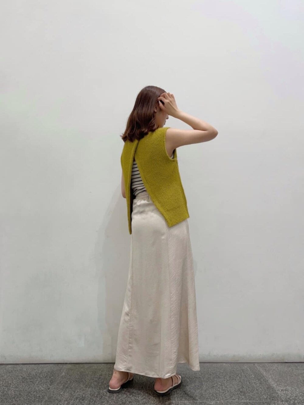 イエロー系のニット/セーター、ホワイト系のキャミソール、ホワイト系のスカートを着用したレディースの夏コーディネートの1枚目の写真