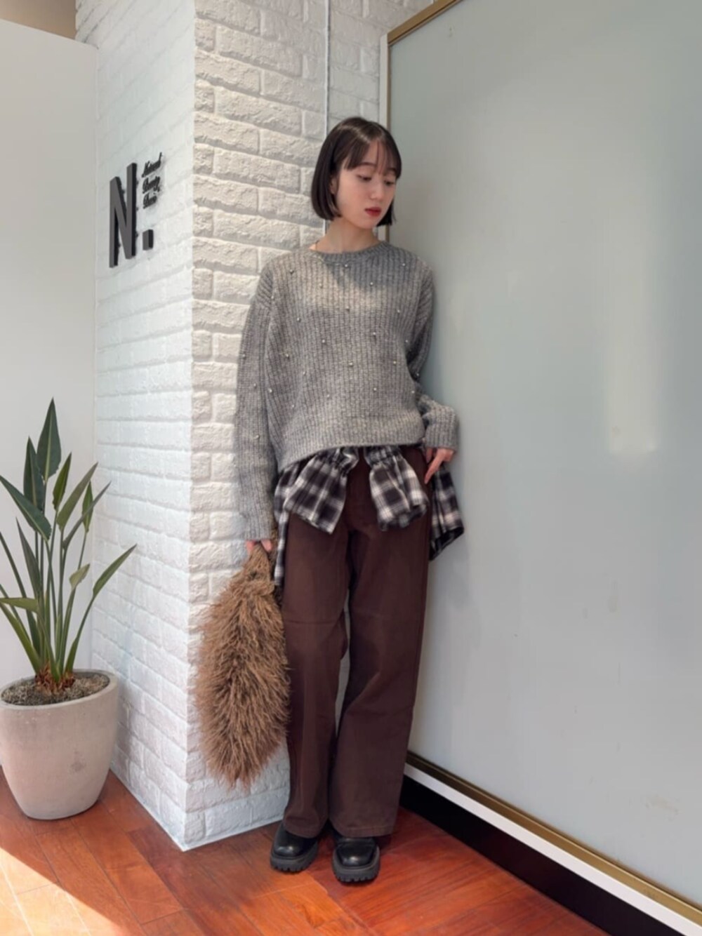 グレー系のニット/セーター、ブラック系のシャツ/ブラウスを着用したレディースの冬コーディネートの1枚目の写真
