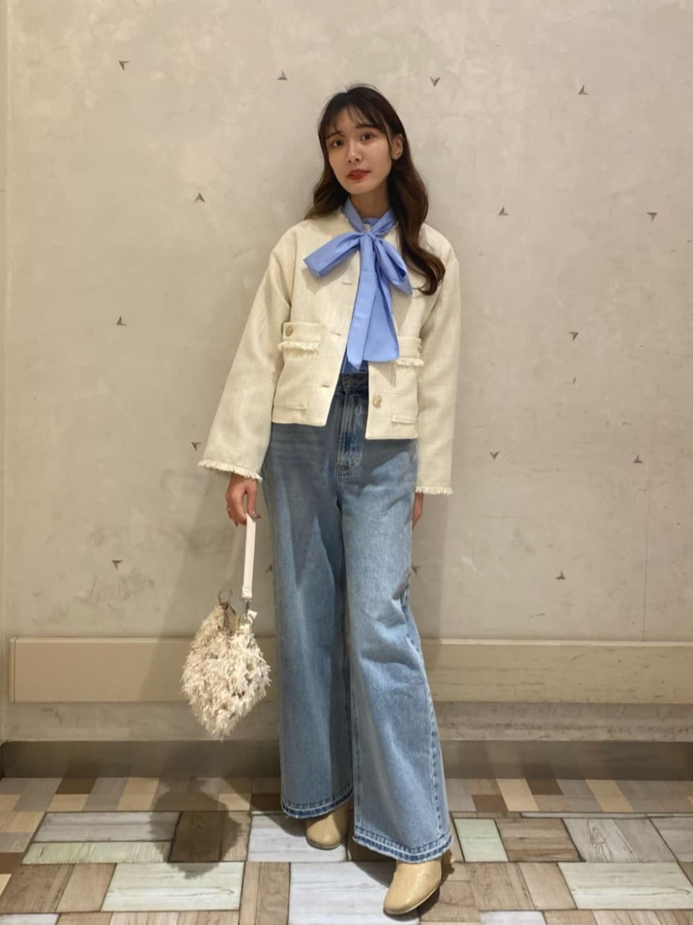 ベージュ系のトートバッグ、ブルー系のデニムパンツ、ブルー系のTシャツ/カットソーを着用したレディースの冬コーディネートの1枚目の写真