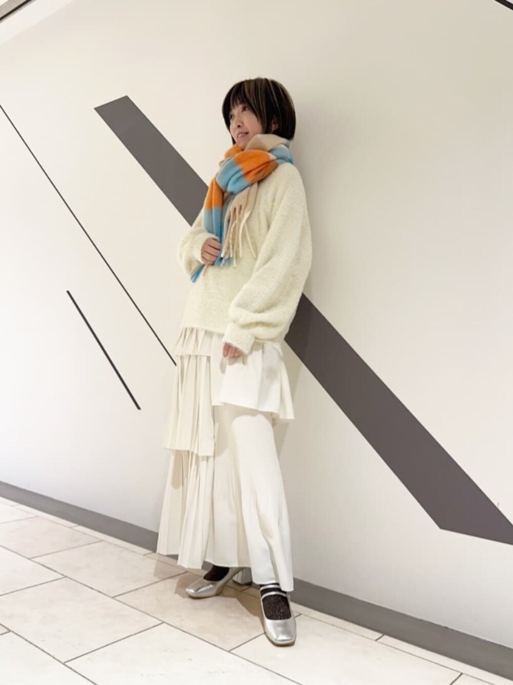 ホワイト系のスカート、ホワイト系のニット/セーター、シルバー系のパンプスを着用したレディースの冬コーディネートの1枚目の写真