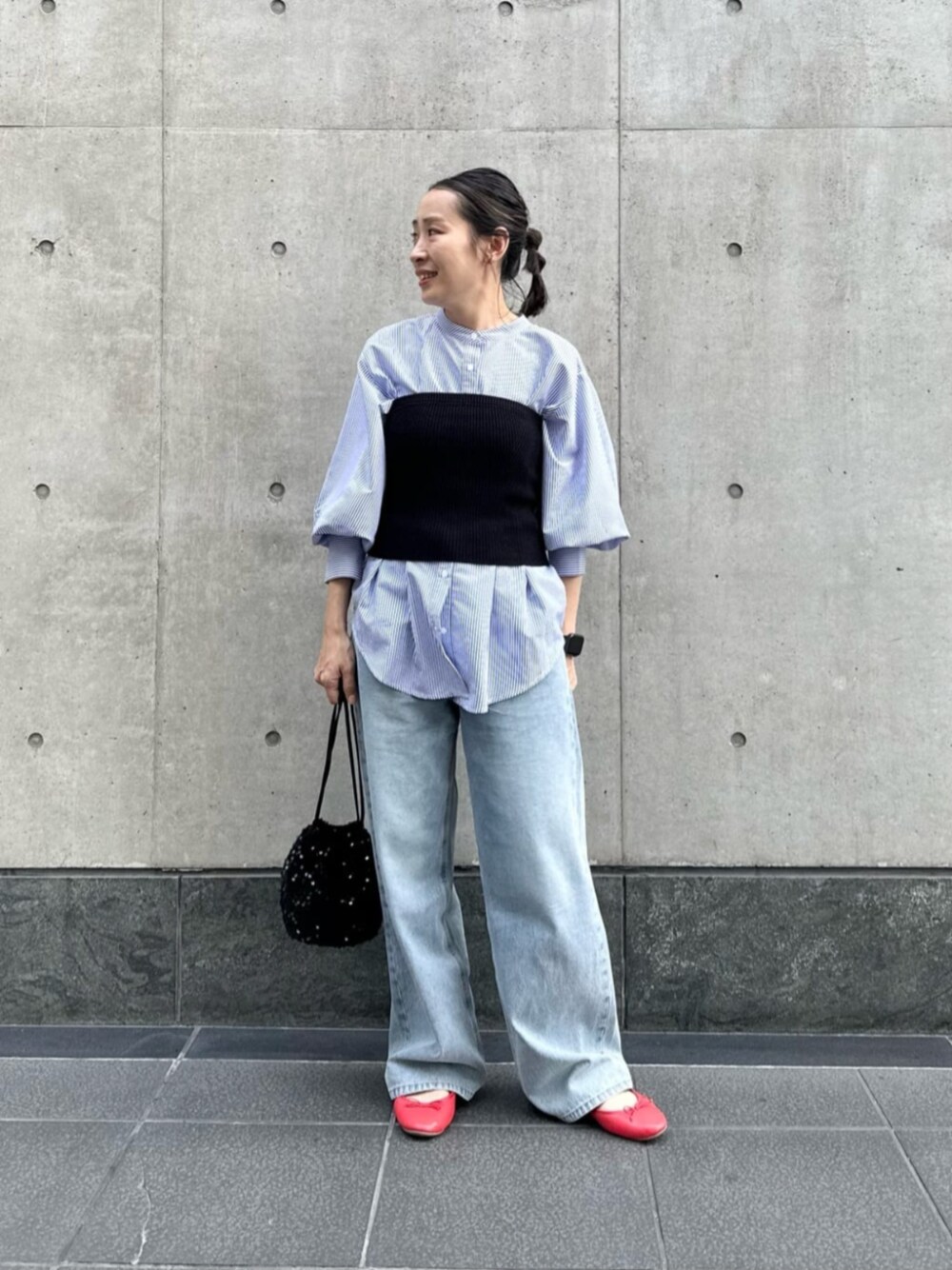 ブラック系のビジネスバッグ、ブラック系のチューブトップ、ブルー系のデニムパンツを着用したレディースの秋コーディネートの1枚目の写真