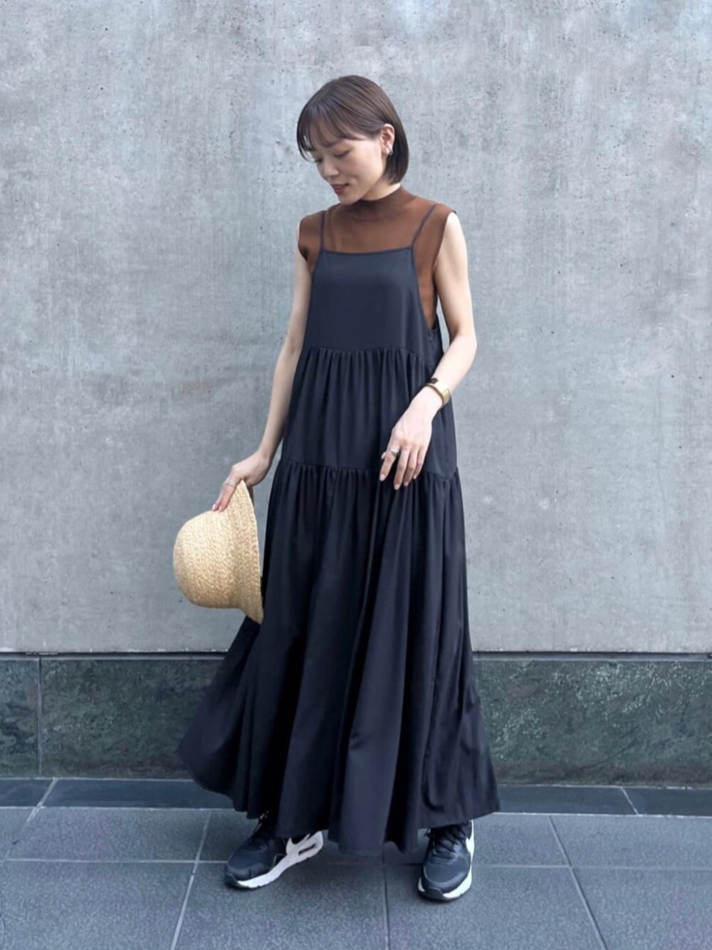 ブラウン系のニット/セーター、ブラック系のワンピース、ゴールド系のネックレスを着用したレディースの夏コーディネートの1枚目の写真