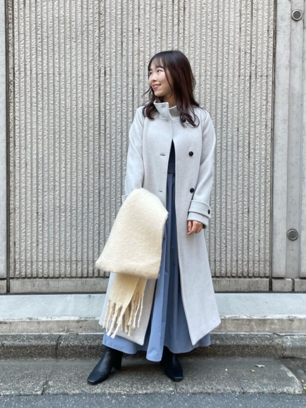 グレー系のワンピース、グレー系のステンカラーコート、ホワイト系のストール/ショールを着用したレディースの冬コーディネートの1枚目の写真