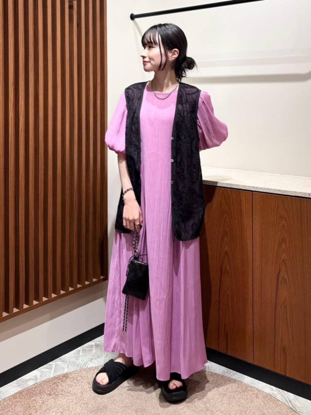 ブラック系のベスト、ピンク系のワンピースを着用したレディースの夏コーディネートの1枚目の写真