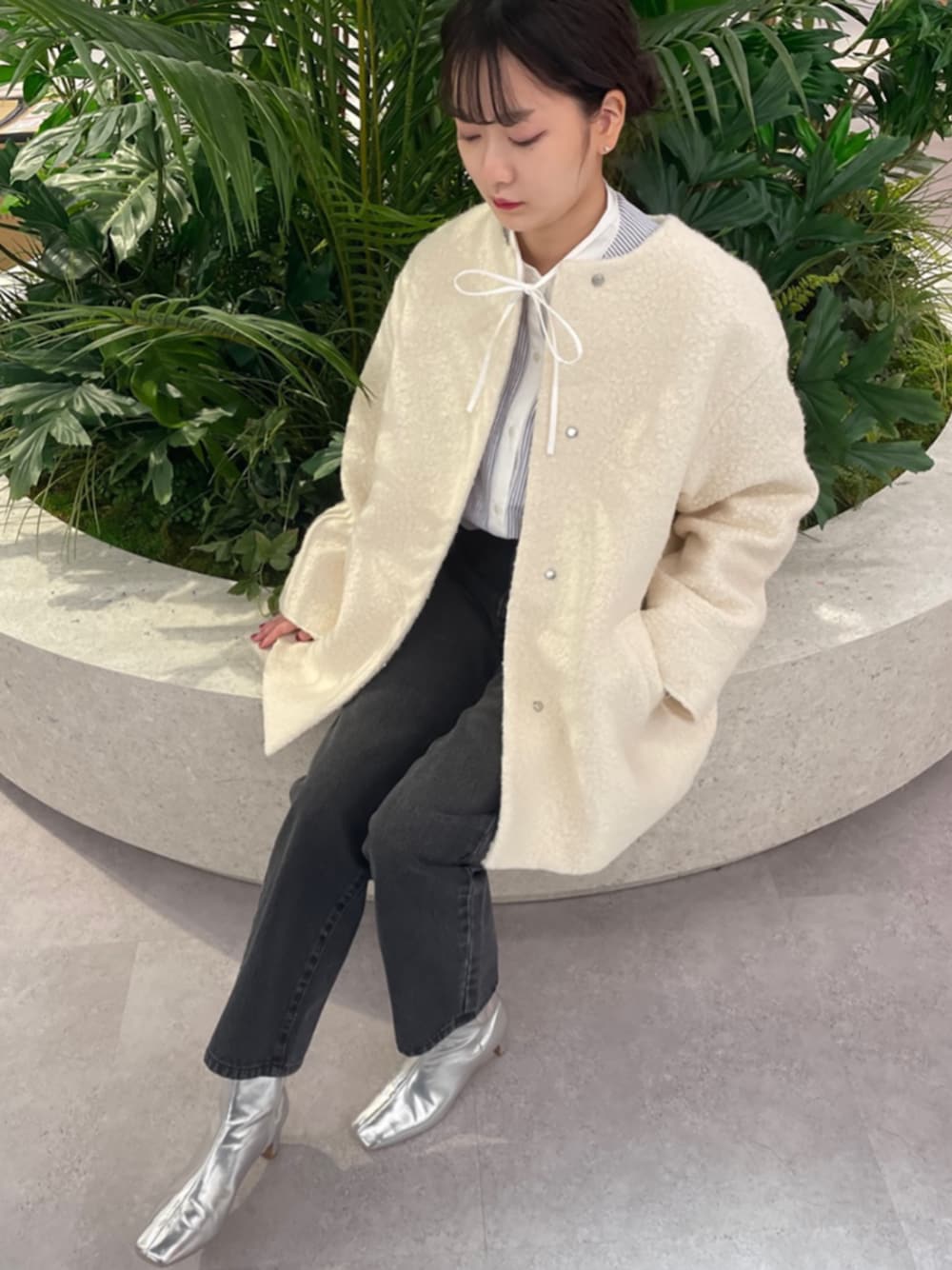 ブラック系のデニムパンツ、シルバー系のブーツ、ホワイト系のノーカラーコートを着用したレディースの秋コーディネートの1枚目の写真