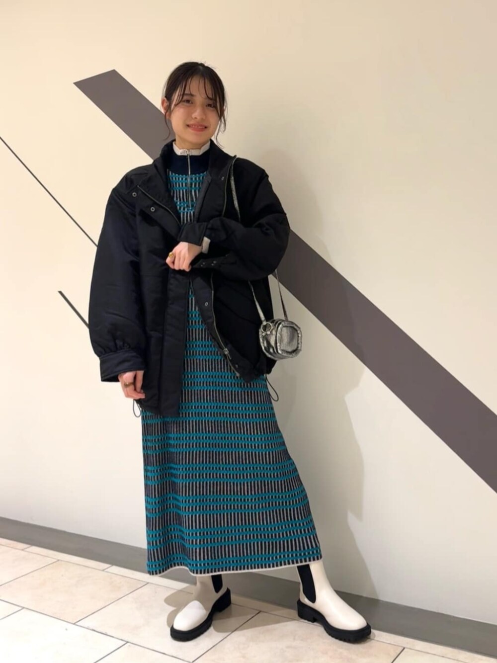 ホワイト系のブーツ、ブルー系のワンピース、ブラック系のブルゾンを着用したレディースの冬コーディネートの1枚目の写真