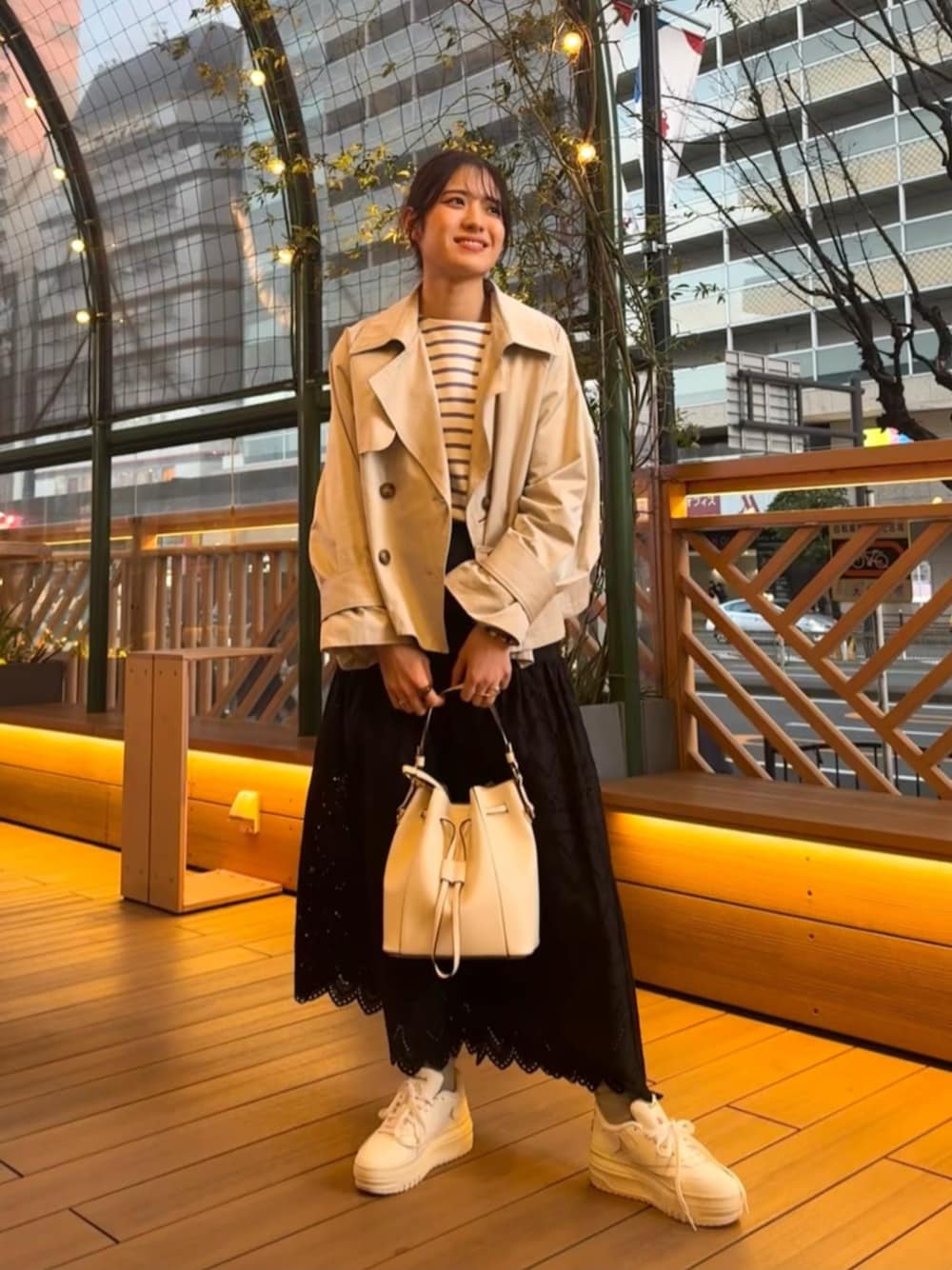 ホワイト系のショルダーバッグ、ブラック系のスカート、ホワイト系のトレンチコートを着用したレディースの春コーディネートの1枚目の写真