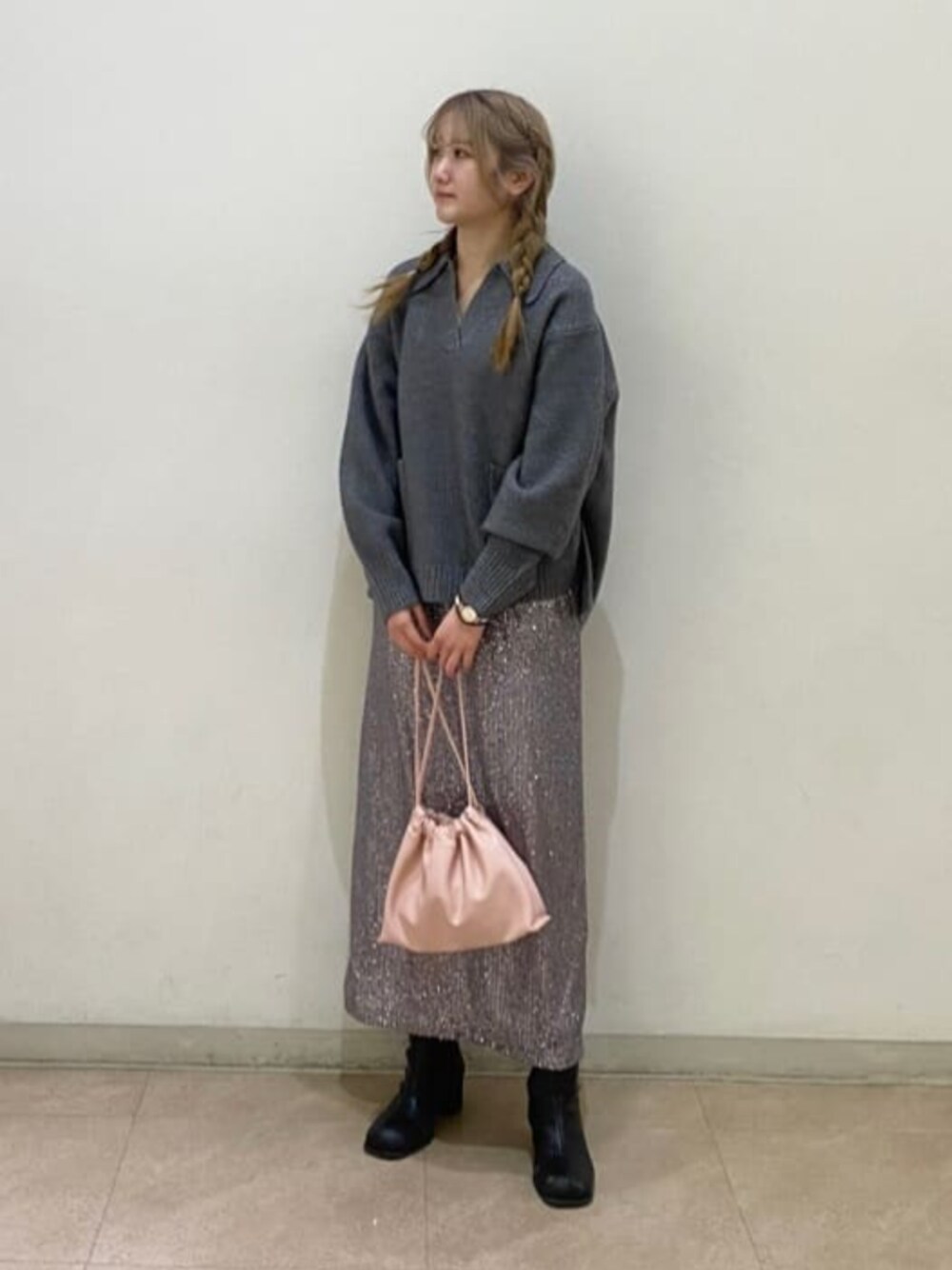 グレー系のニット/セーター、グレー系のスカート、ピンク系のビジネスバッグを着用したレディースの冬コーディネートの1枚目の写真