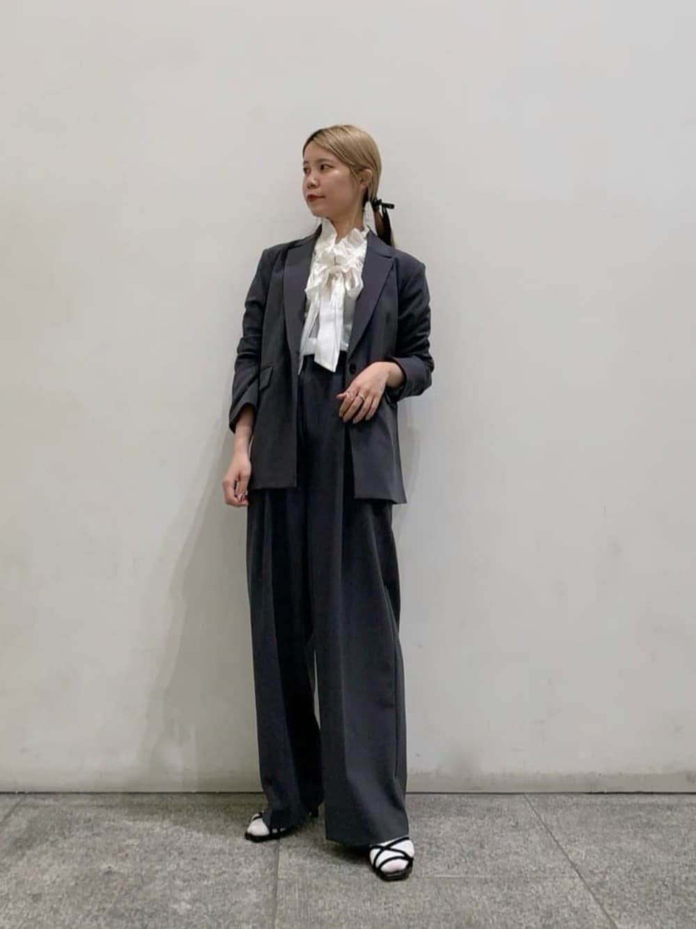 グレー系のテーラードジャケット、グレー系のその他パンツ、ホワイト系のシャツ/ブラウスを着用したレディースの春コーディネートの1枚目の写真