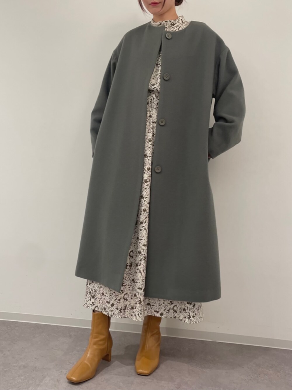 グリーン系のノーカラーコート、ホワイト系のワンピース、ベージュ系のブーツを着用したレディースの秋コーディネートの1枚目の写真