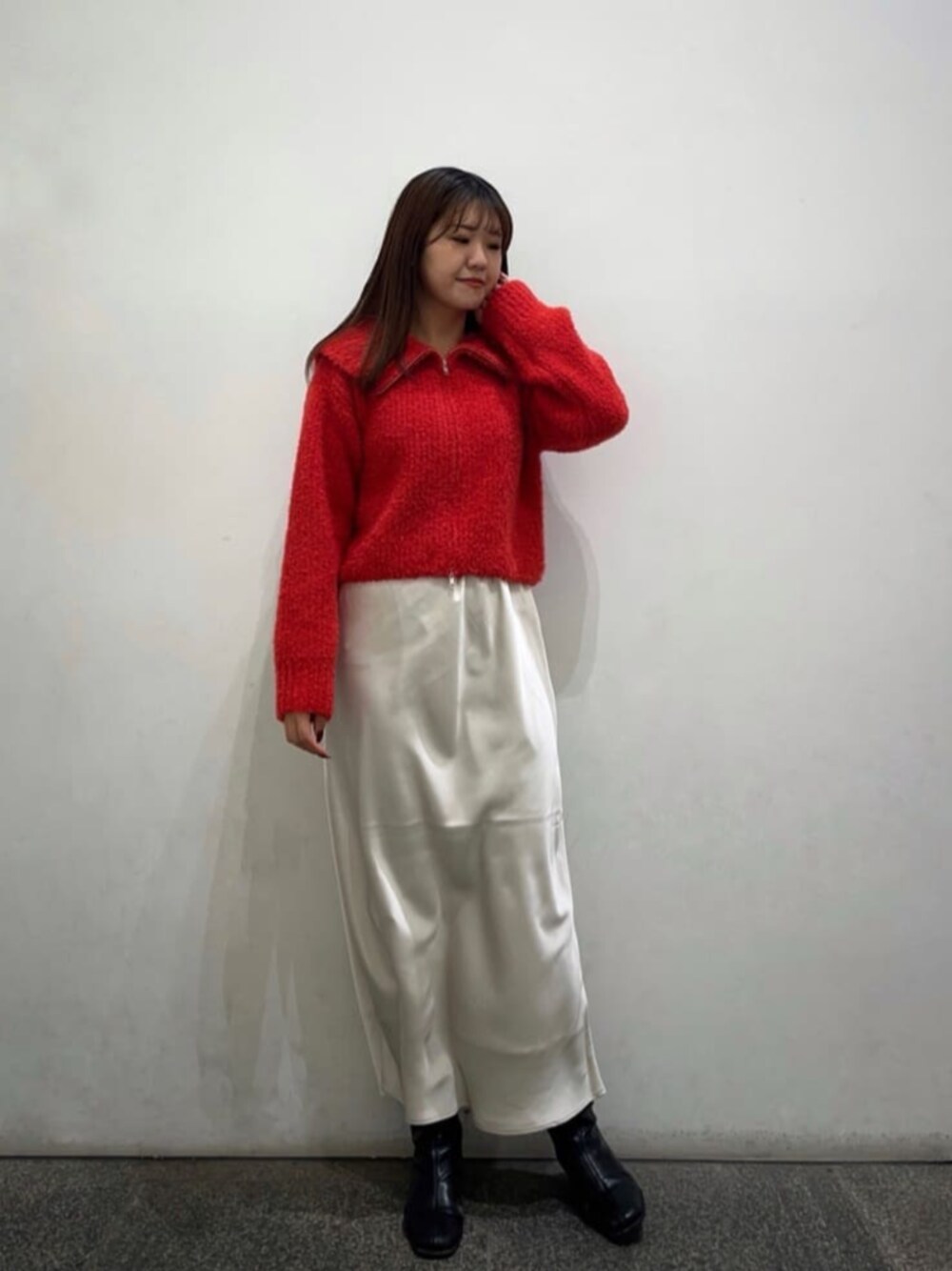 ブラック系のブーツ、レッド系のニット/セーター、ホワイト系のスカートを着用したレディースの冬コーディネートの1枚目の写真