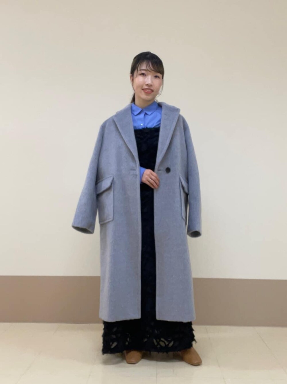 ブルー系のシャツ/ブラウス、ブラック系のワンピース、グレー系のチェスターコートを着用したレディースの冬コーディネートの1枚目の写真