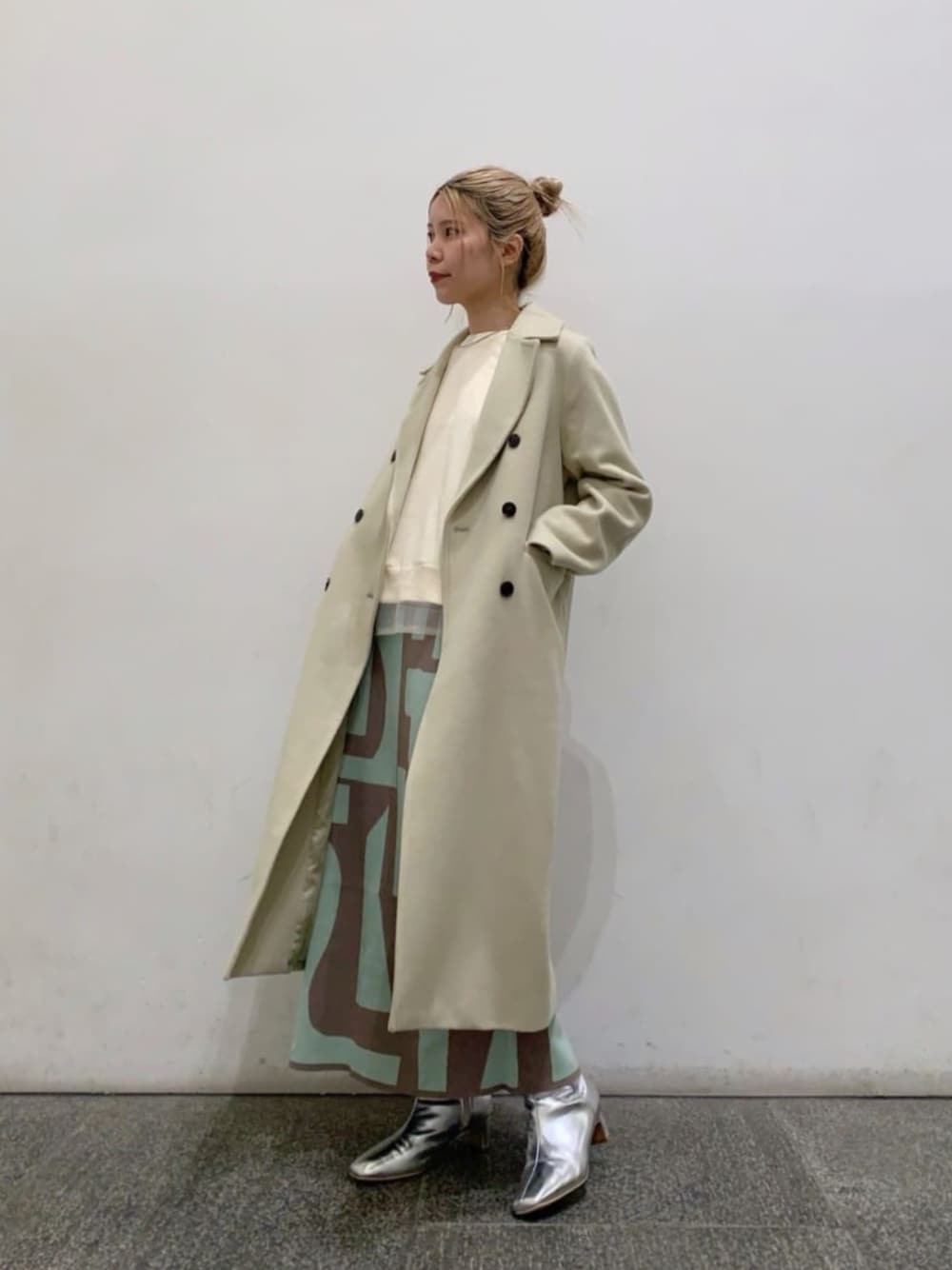 ベージュ系のスカート、シルバー系のブーツ、グリーン系のチェスターコートを着用したレディースの冬コーディネートの1枚目の写真