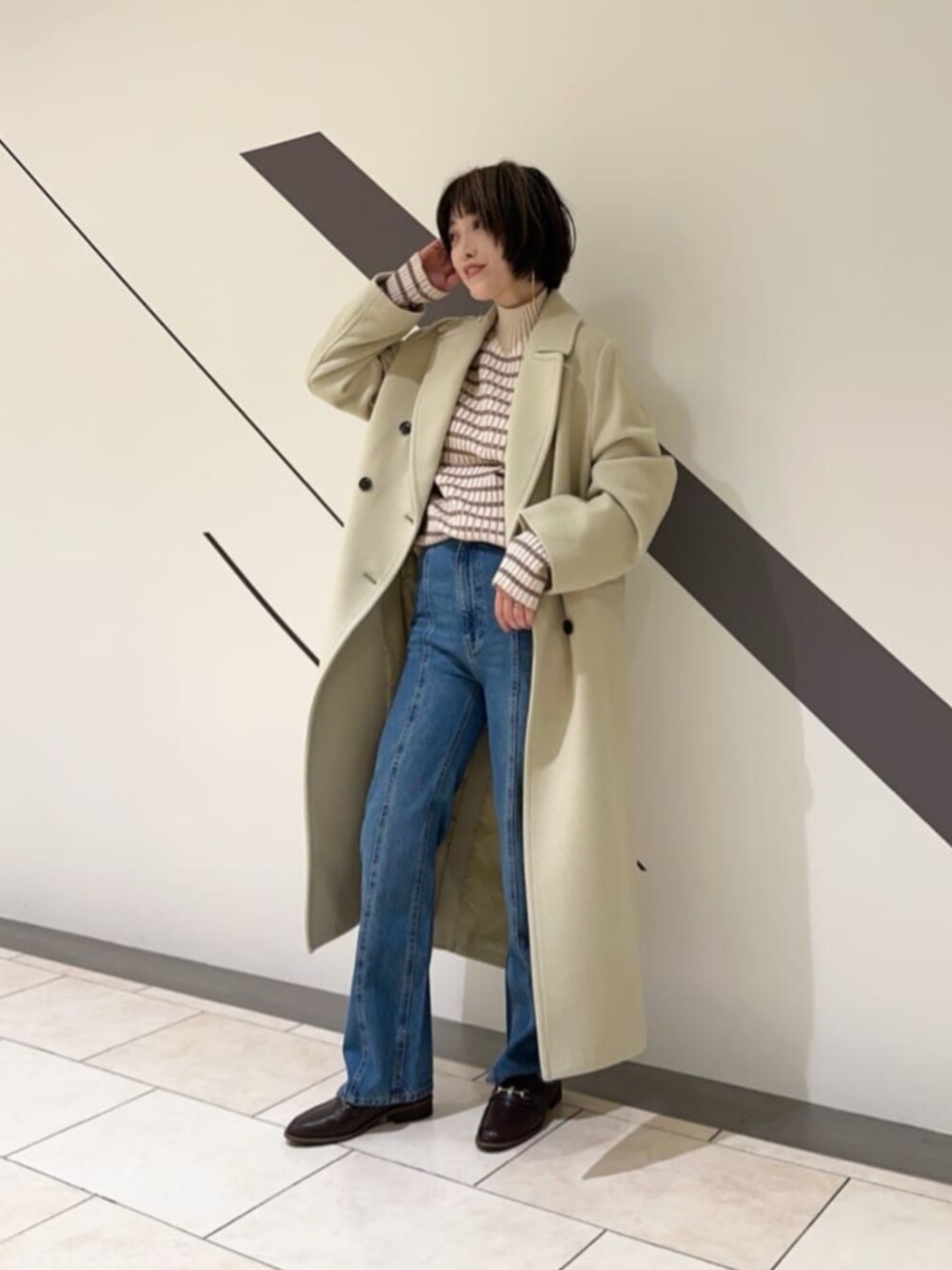 ブラック系のローファー、グリーン系のチェスターコート、ホワイト系のニット/セーターを着用したレディースの秋コーディネートの1枚目の写真