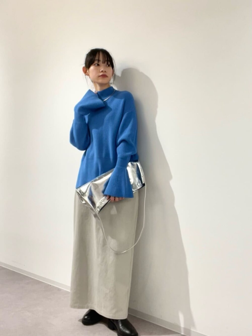 ブルー系のニット/セーター、グレー系のスカート、シルバー系のビジネスバッグを着用したレディースの冬コーディネートの1枚目の写真