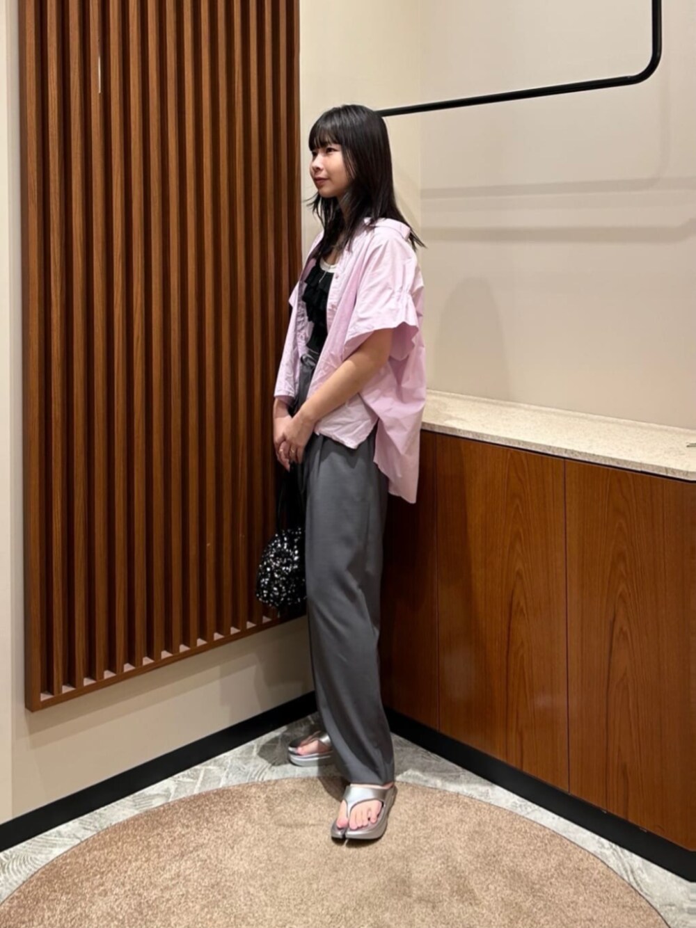 ブラック系のショルダーバッグ、ホワイト系のキャミソール、ブラック系のベストを着用したレディースの夏コーディネートの1枚目の写真