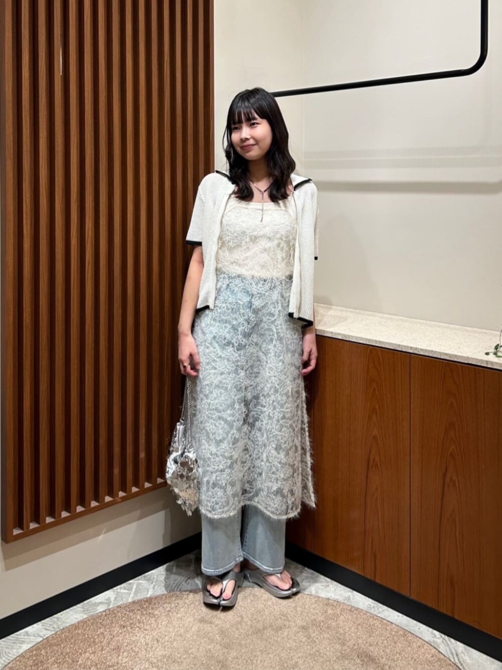 シルバー系のショルダーバッグ、ホワイト系のワンピース、ホワイト系のカーディガン/ボレロを着用したレディースの夏コーディネートの1枚目の写真