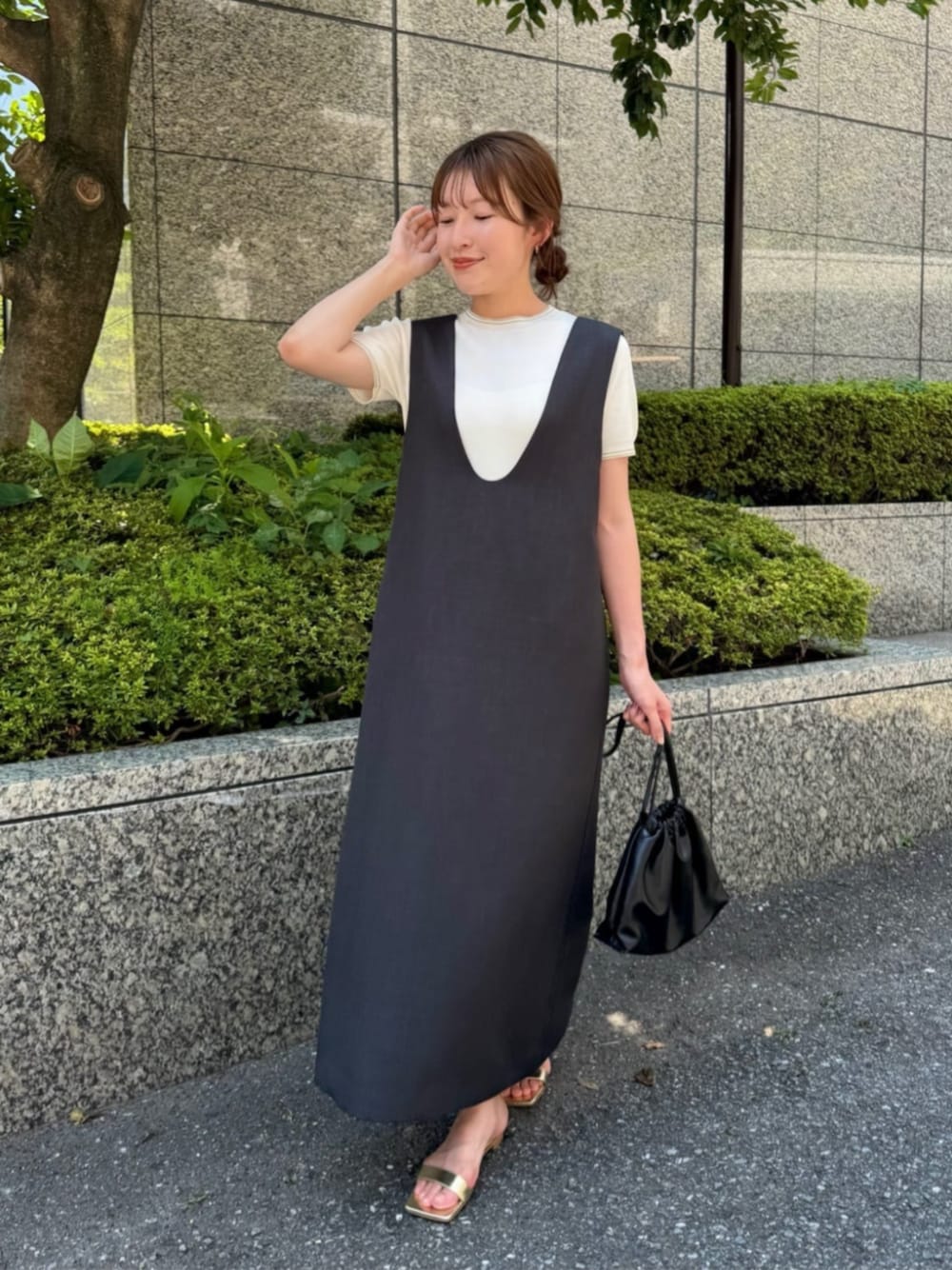 グレー系のジャンパースカート、ホワイト系のニット/セーターを着用したレディースの夏コーディネートの1枚目の写真