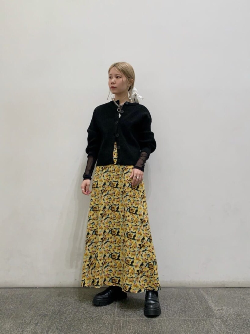 ブラック系のTシャツ/カットソー、イエロー系のスカート、ブラック系のカーディガン/ボレロを着用したレディースの冬コーディネートの1枚目の写真