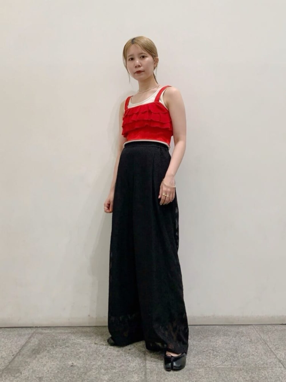 ホワイト系のタンクトップ、ブラック系のスラックス、レッド系のベストを着用したレディースの春コーディネートの1枚目の写真