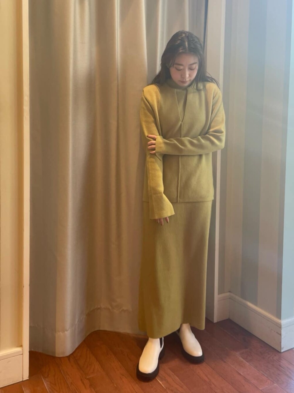 ホワイト系のブーツ、イエロー系のワンピースを着用したレディースの冬コーディネートの1枚目の写真