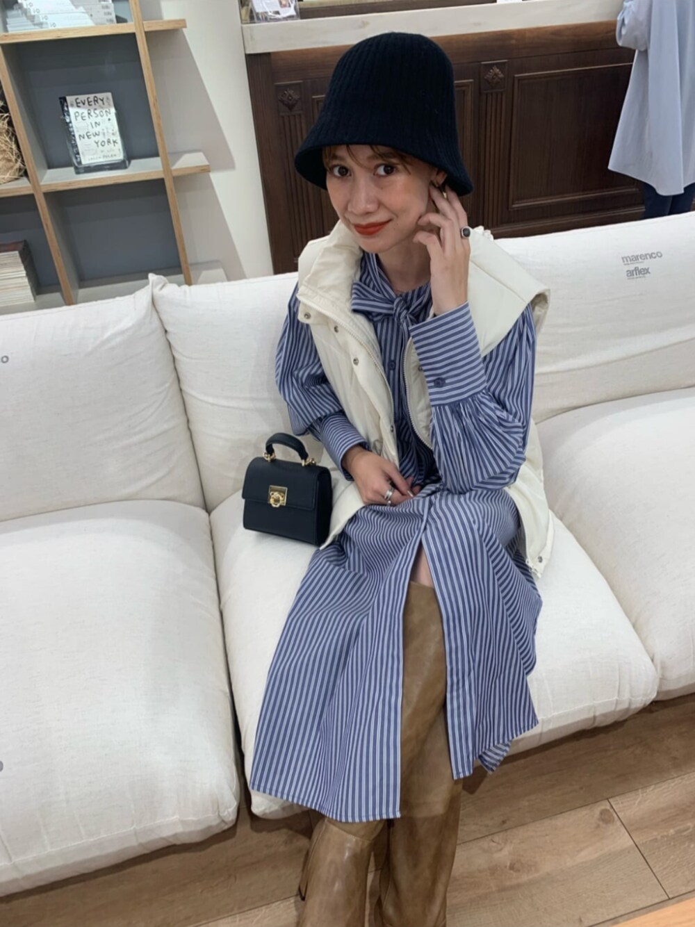 ブラック系のショルダーバッグ、ホワイト系のベスト、ブルー系のシャツワンピースを着用したレディースの夏コーディネートの1枚目の写真