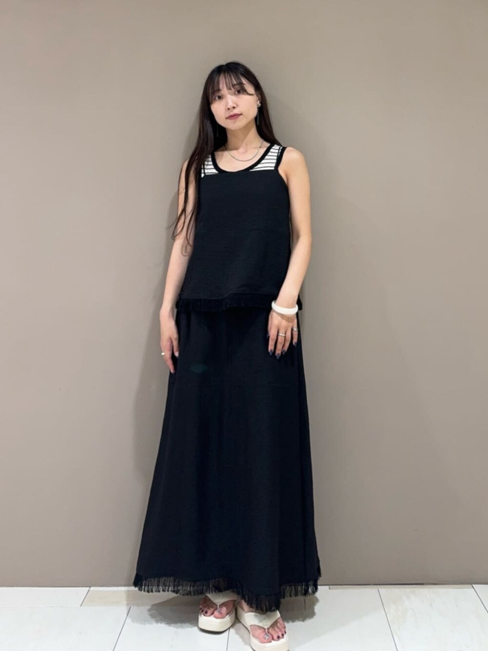 ホワイト系のサンダル、ホワイト系のタンクトップ、ブラック系のワンピースを着用したレディースの夏コーディネートの1枚目の写真