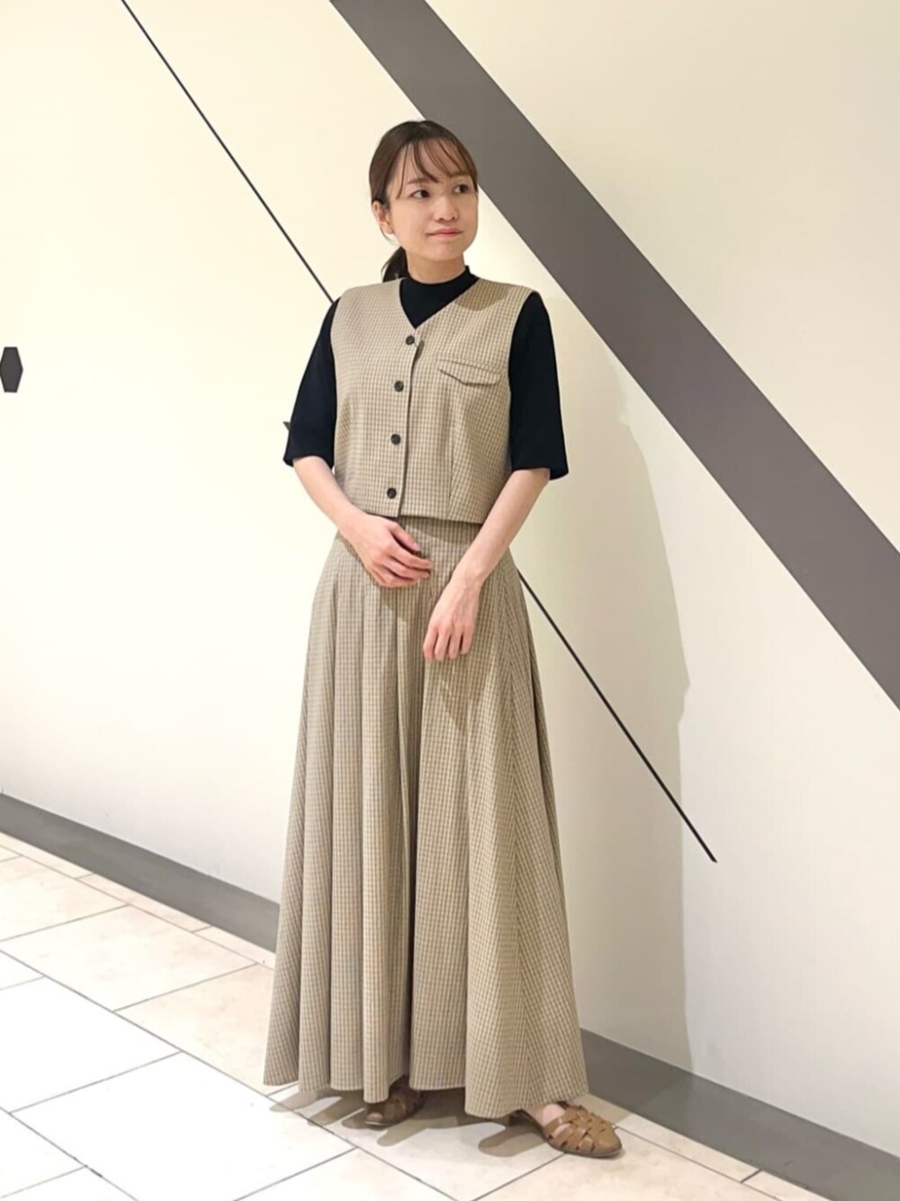 ベージュ系のワンピース、ブラック系のニット/セーターを着用したレディースの春コーディネートの1枚目の写真